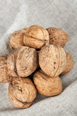 A stack of hard shells of walnuts piled together on light grey fabric cotton tablecloth, selective focus