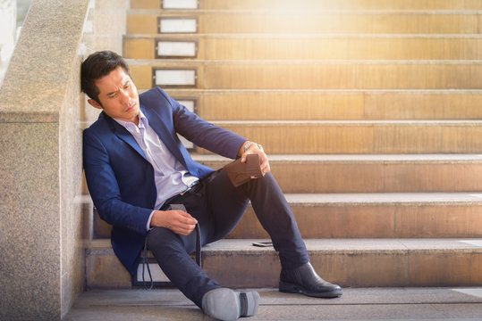 Sad businessman sitting on steps outside office.