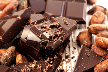 Broken dark chocolate, cocoa powder and coffee beans on a wooden table