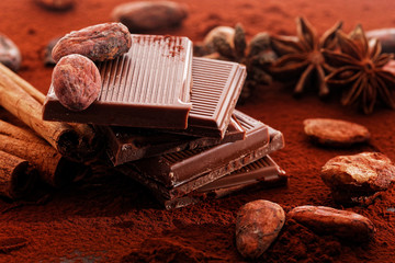 Broken dark chocolate, cocoa powder and coffee beans on a wooden table