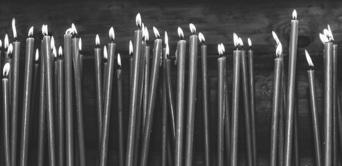 many burning wax candles in the temple, black and white photo