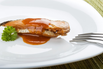 Marinated herring fish with tomato sauce on plate with fork