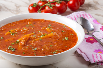 Tomato creamy soup with carrot and rice in white bowl with spoon