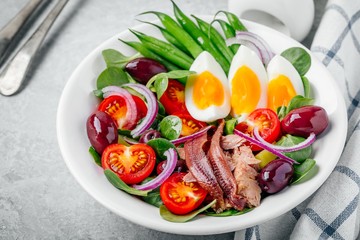 nicoise salad with tuna, anchovies, eggs, green beans, olives, tomatoes, red onions and salad leaves