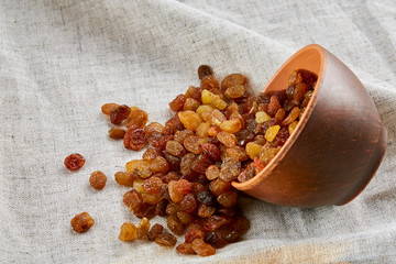 Ceramic bowl with golden raisins on light tablecloth, close-up, selective focus
