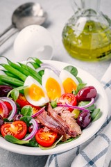 nicoise salad with tuna, anchovies, eggs, green beans, olives, tomatoes, red onions and salad leaves