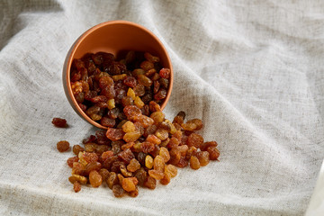 Ceramic bowl with golden raisins on light tablecloth, close-up, selective focus