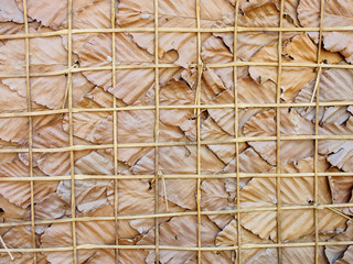 Close-up detail of a simple natural wall made out of large dried leaves with a wooden bamboo frame. Nakhon Ratchasima, Thailand. Travel and tropics concept.