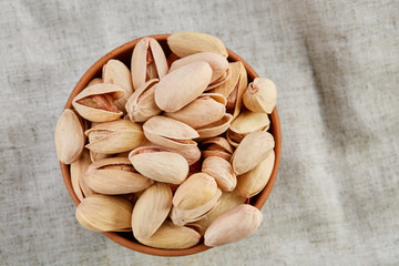 Unpeeled pistachios in ceramic bowl closeup, selective focus