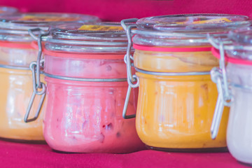 Glass jars with different sorts of honey on red background