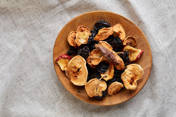 Close-up wooden bowl with dried fruits on a light tablecloth