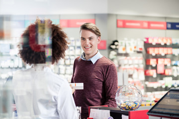 Young man smiling while buying an useful pharmaceutical product