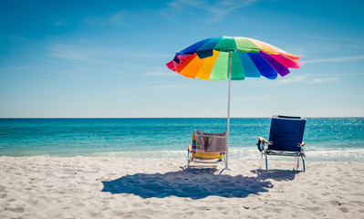 two deckchairs on the beautiful beach turquoise sea and an umbrella - obrazy, fototapety, plakaty