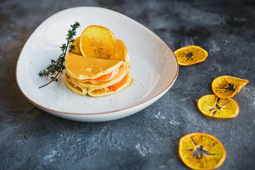Pancakes with salmon fish in white plate and dried citrus. Tasty food.