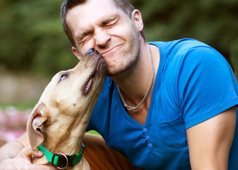 guy with his dog hugging in the park