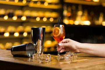a female hand holds old fashioned cocktail standing on the bar
