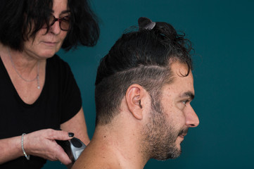 Obraz premium Female barber working with hair clipper, shaving young man's neck