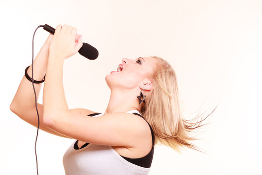 Blonde woman singing to microphone, profile view