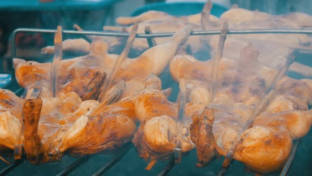 Whole chicken carcass grill strung on wooden stick grilling on the grill. Street Food Thailand