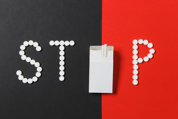 Medication white round tablets in word Stop. Creative composition with message Stop smoke cigarettes on red black background. Concept of health, choice, healthy lifestyle. Copy space advertisement.
