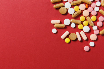 Medication white colorful round tablets arranged abstract on red color background. Aspirin, capsule pills for design. Health, treatment, choice healthy lifestyle concept. Copy space advertisement.