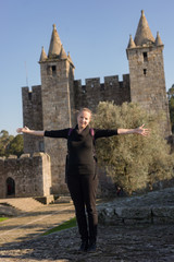 Caucasian woman posing in front of medieval gothic public castle in Portugal on sunny day