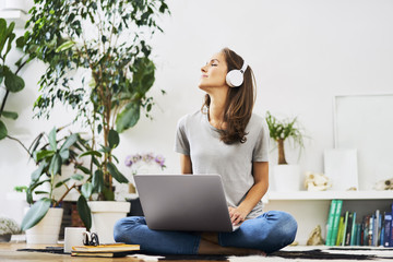 Young woman listening to music on laptop while sitting at home