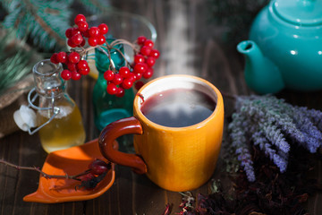 Herbal tea from the viburnum decoction of red sea buckthorn berries and thyme in a transparent glass mug in the village on a wooden table