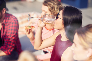 Pleasant young woman drinking wine with her friends