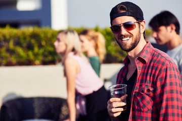 Joyful bearded man drinking beer at the party