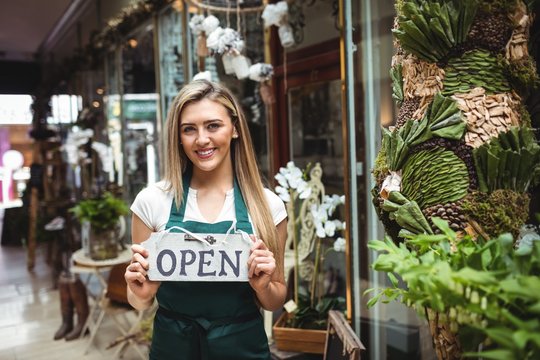 Female florist holding open signboard