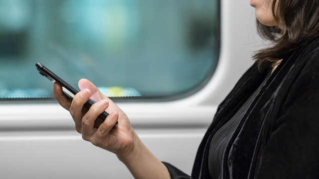 Woman In Black Uses Black Mobile Phone On Train Or Bus