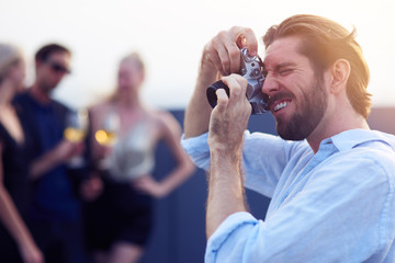 Handsome photographer making photos at the party