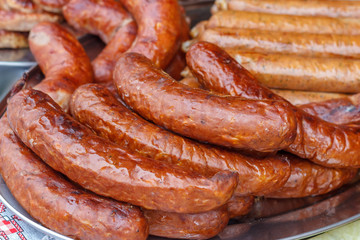 Fresh, hot sausages cooked on the grill, outdoors, on the coals.