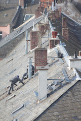 Roofer repairs shingle on rooftop