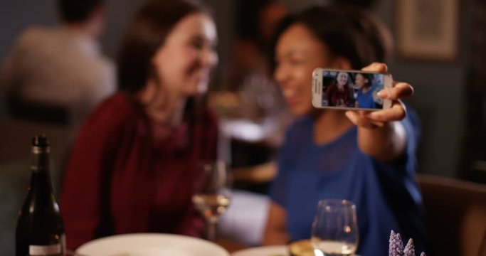 4K Beautiful fun female friends pose to take a selfie with camera phone in restaurant.