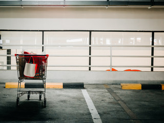 shopping cart in empty area of car parking in shopping mall with soft focus shopping mall background