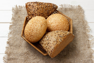 Bread rolls in the basket on rustic wooden background