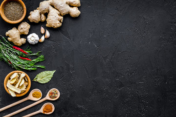 Condiments, seasoning and spices concept. Dry spices in wooden spoons near ginger, rosemary, chili pepper on black background top view copy space