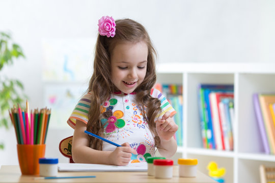 Cute little preschooler child girl drawing at home