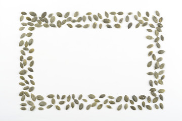 Pipas de calabaza peladas sobre fondo blanco, composición como marco