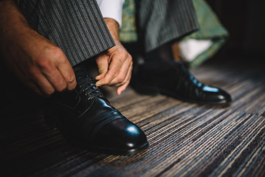 Business man wearing classic shoes. Groom preparing on wedding day and tying laces