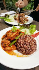 Fried chilly paste with pork, meat with stream rice and ice tea on wooden table.