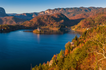 Bled, Slovenia - Panoramic skyline view of Lake Bled with warm autumn foliage and the famous Pilgrimage Church of the Assumption of Maria and the Alps at background