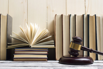 Legal Law concept - Open law book with a wooden judges gavel on table in a courtroom or law...