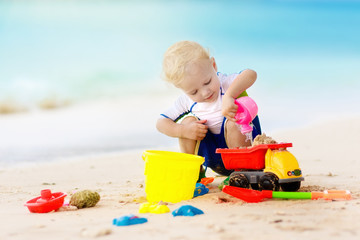Kids play on tropical beach. Sand and water toy.