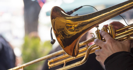 Musician with brass trumpet plays classical music. Close up view with details, blurred background.