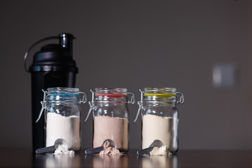 Composition with protein shake, powder and dumbbell on table