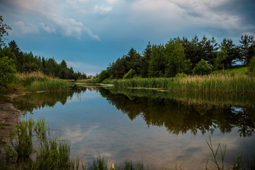 Fototapeta na wymiar Calm river flowing gently through woodland landscape. Location Lagen in Belarus