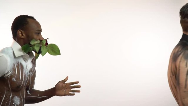 Muscular men with roses in their teeth dance and turn to the camera